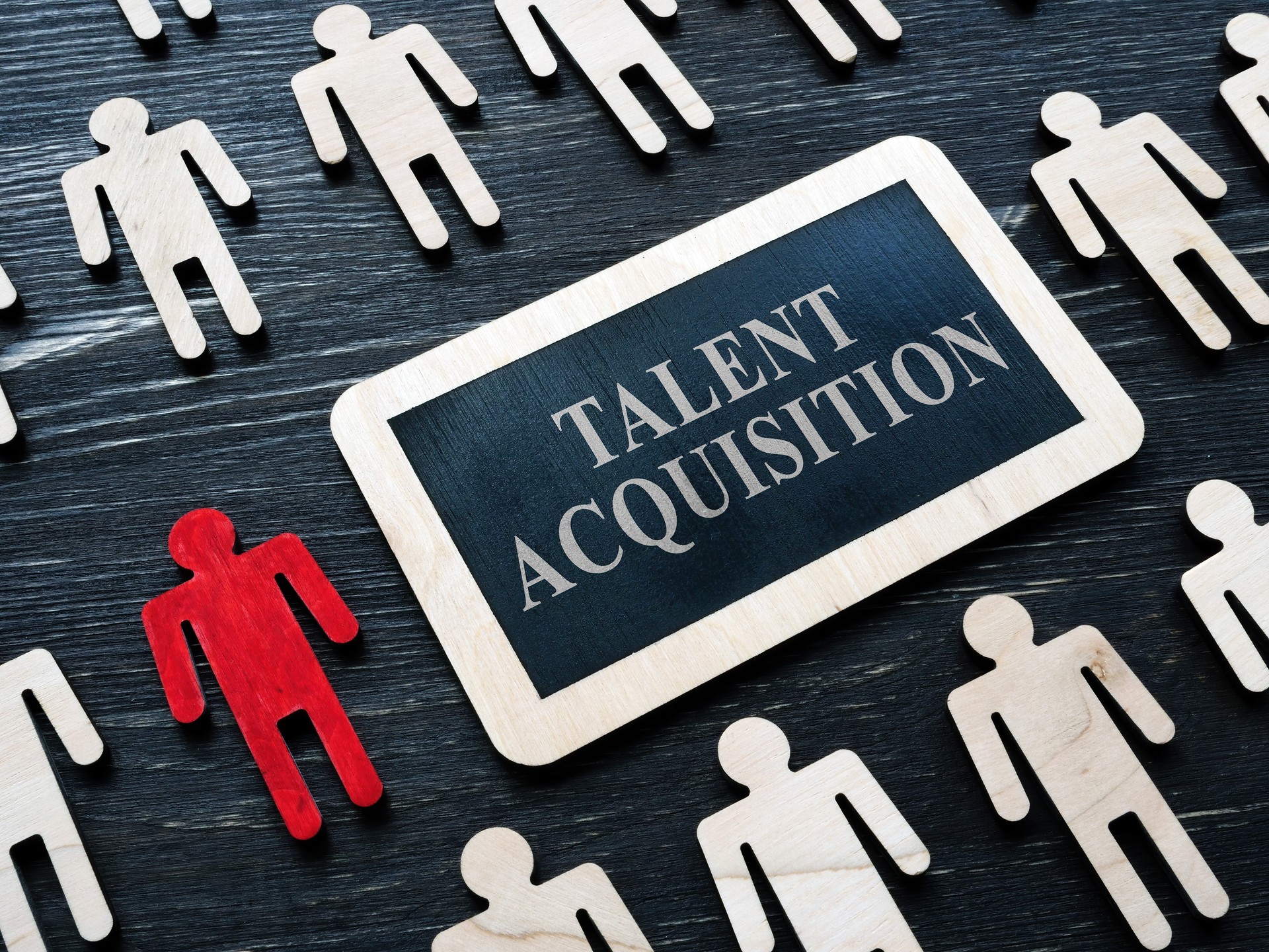 Talent acquisition concept. Small plaque and small wooden figures.